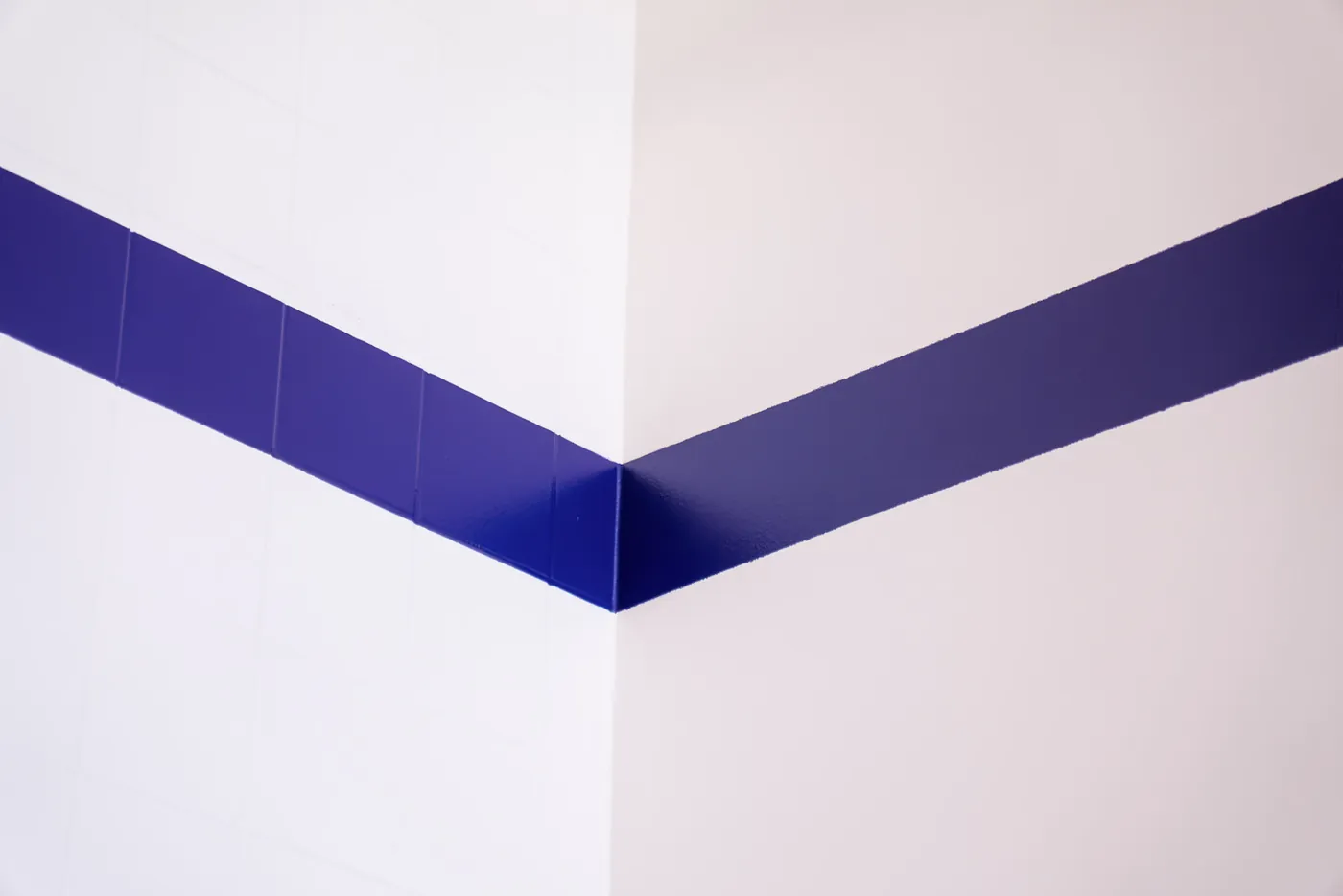 Angle de mur blanc traversé par une frise de carreaux bleus
